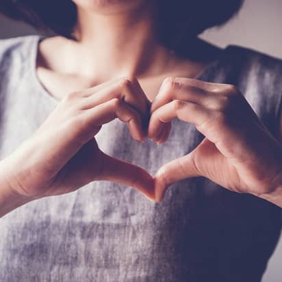 woman holding her hands in the shape of a heart