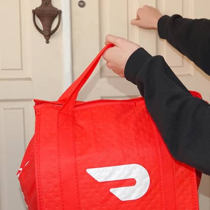 door dash delivery person knocking on a door while holding a door dash bag