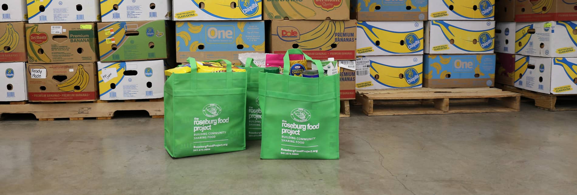 green bags for the Food Project in front of boxes of food
